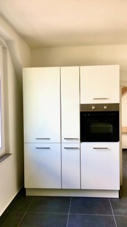 Küche mit weißen Hochschränken und Backofen